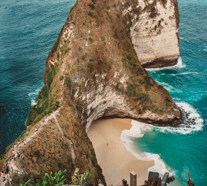 Turquoise water and a green coastal cliff at Kelingking Beach, Bali