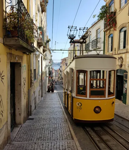 A sunlit street and yellow tram in Lisbon